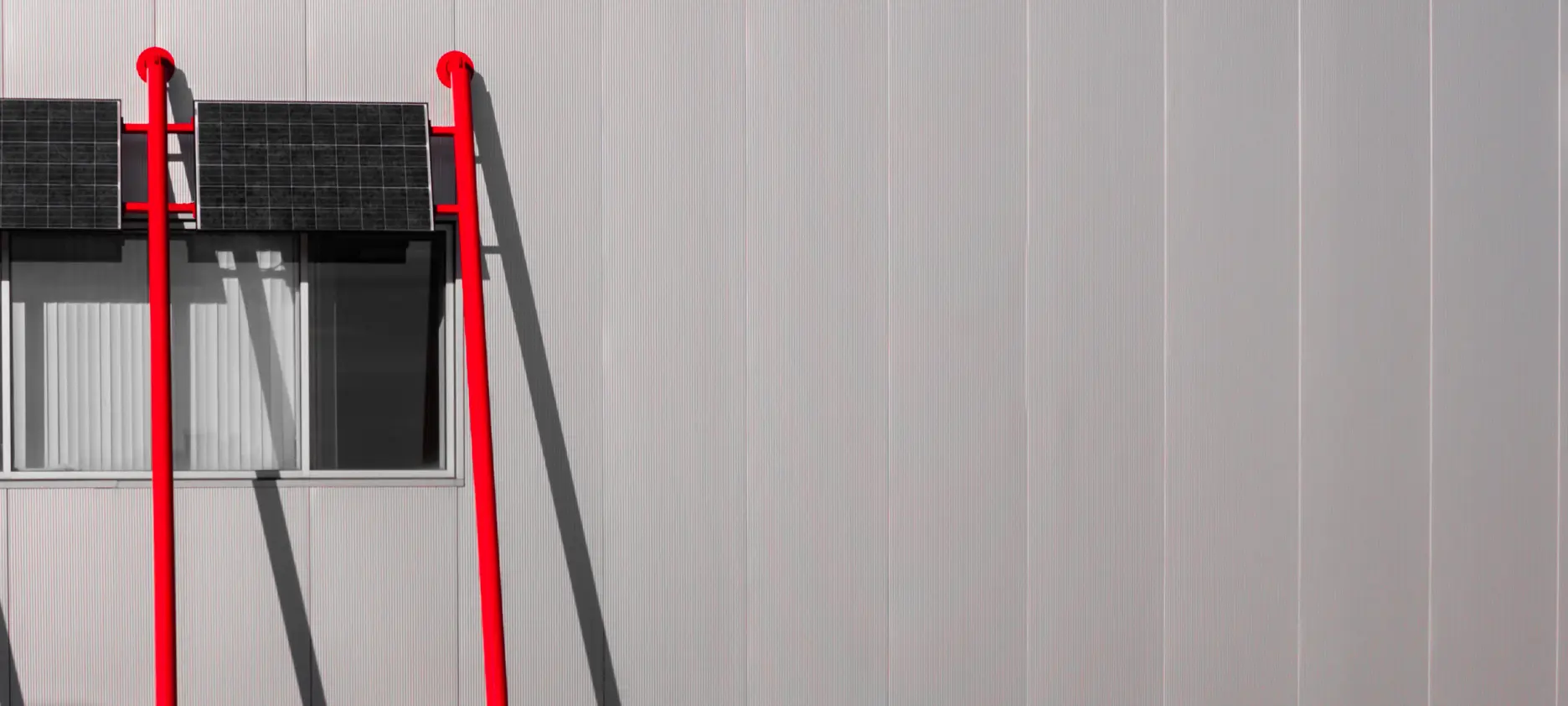 A red ladder on a grey wall
